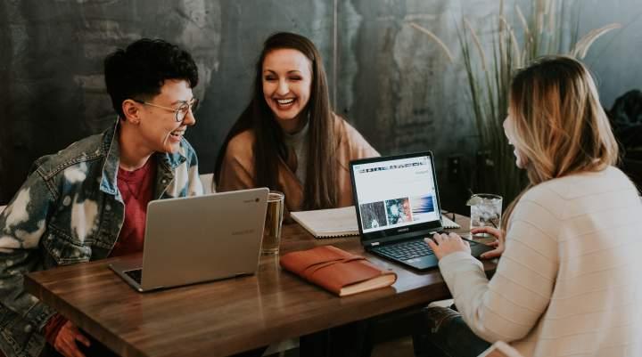 People sit at a table with laptops 